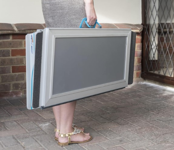 A Lady Carrying A Grey Portable Ramp With Blue Handle