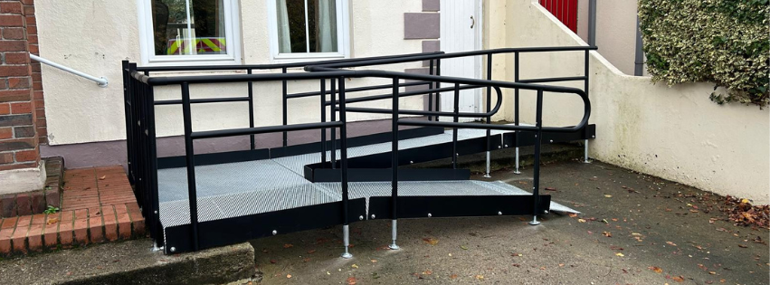 Modular ramp with black handrails at the front of a house