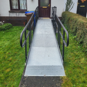 A metal modular ramp recently installed at a brown front door